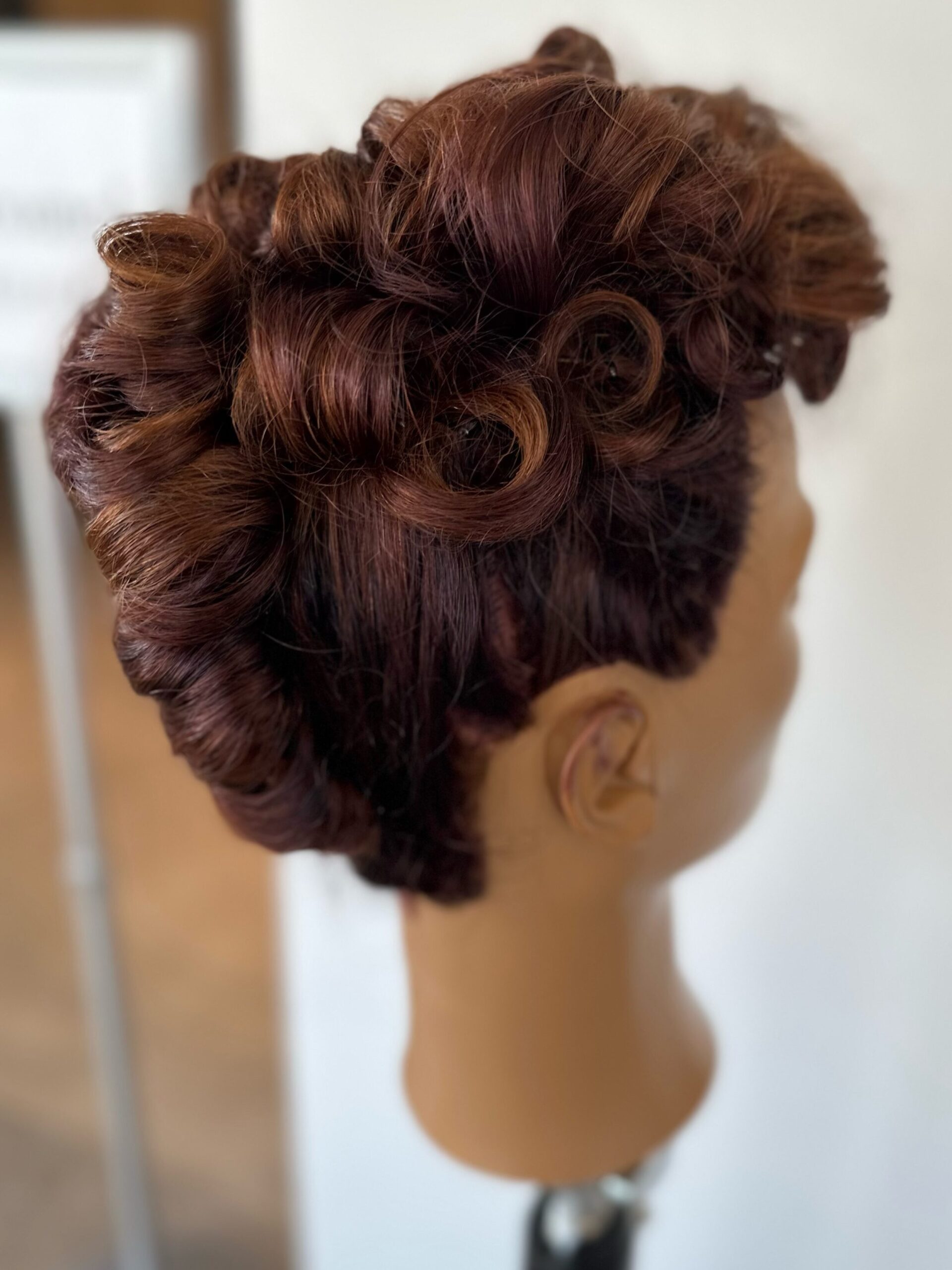 Formal hair for prom or wedding. Hairstyle where mountains of curls are piled on the back and top of head. Mannequin is facing right.