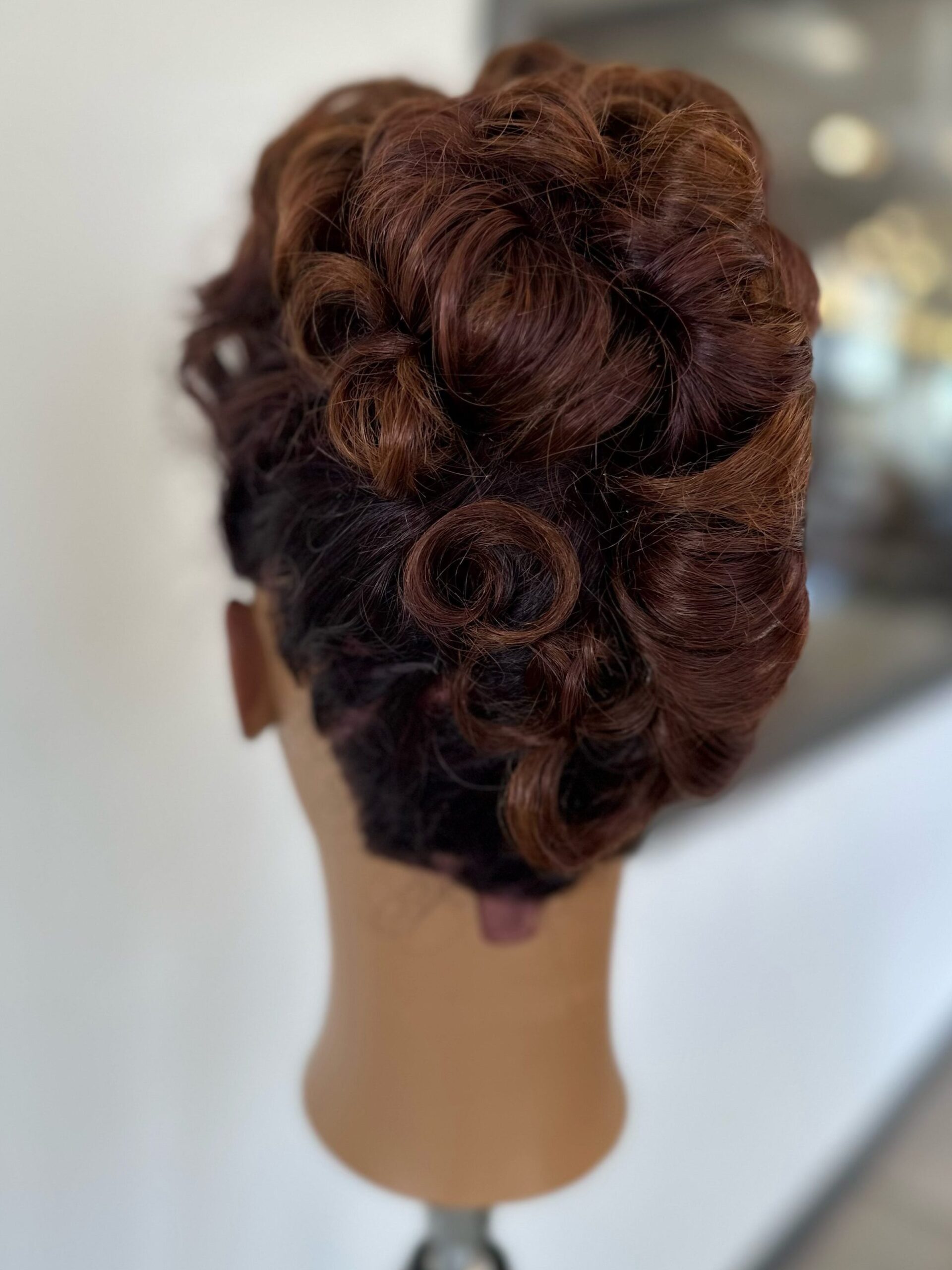 Formal hair for prom or wedding. Hairstyle where mountains of curls are piled on the back and top of head. Mannequin is facing away.