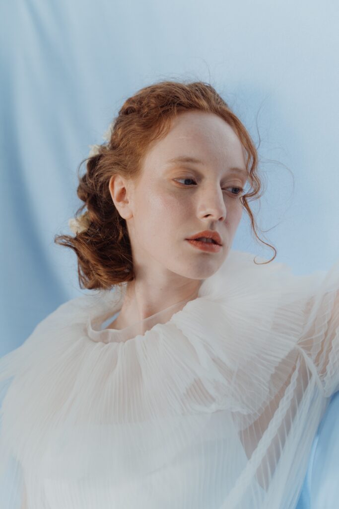 Prom or wedding hair style on a red haired woman with a white, frilly dress
