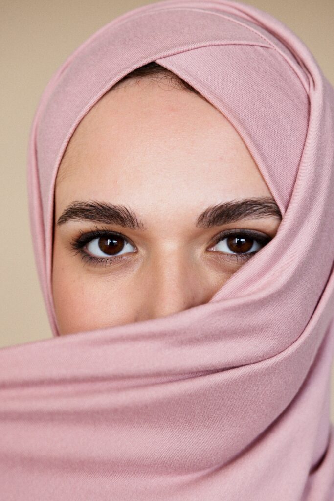 Woman in a pink head scarf shows off beautiful brown eyes and dark eyebrows