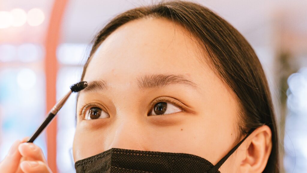 Woman wearing a mask gets eyebrows brushed upward