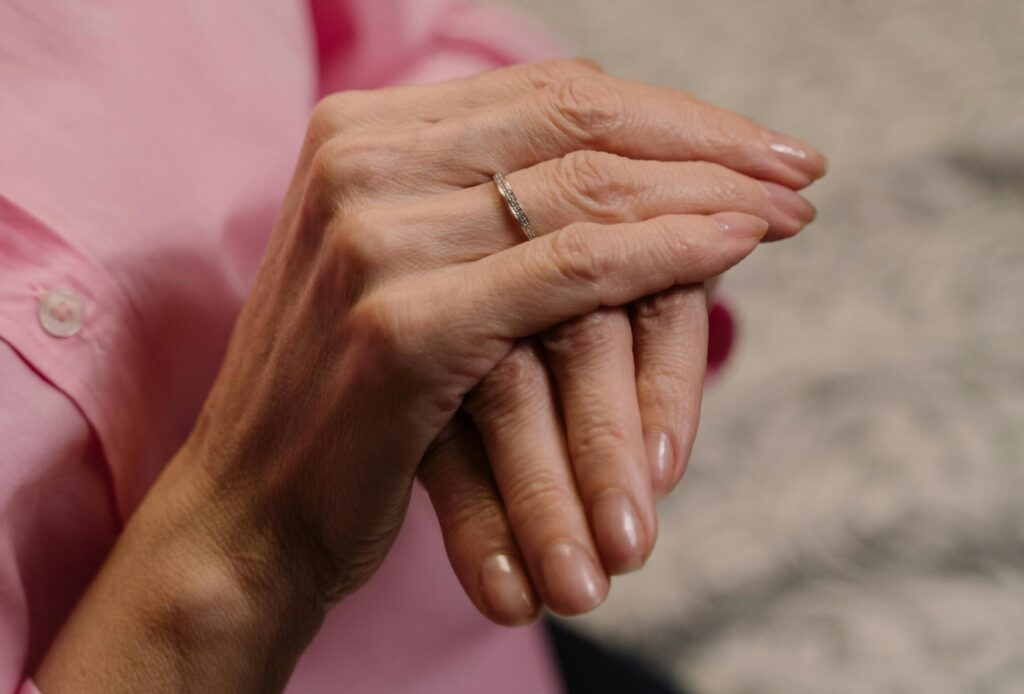 Hands folded over each other, showing off shiny, natural nails
