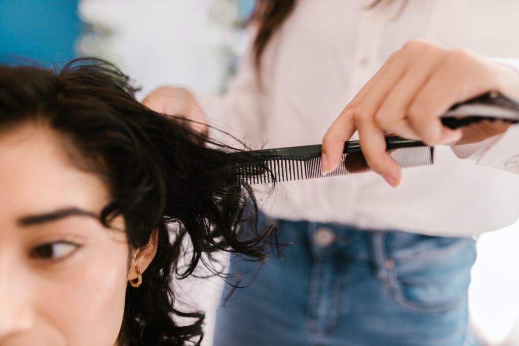 Hairstylist combs through client's hair
