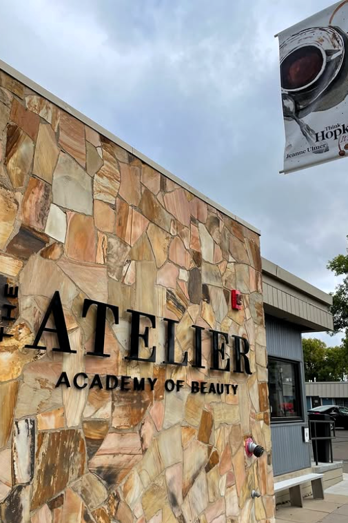 A side view of the Atelier Academy of Beauty and a pole featuring a Hopkins city banner