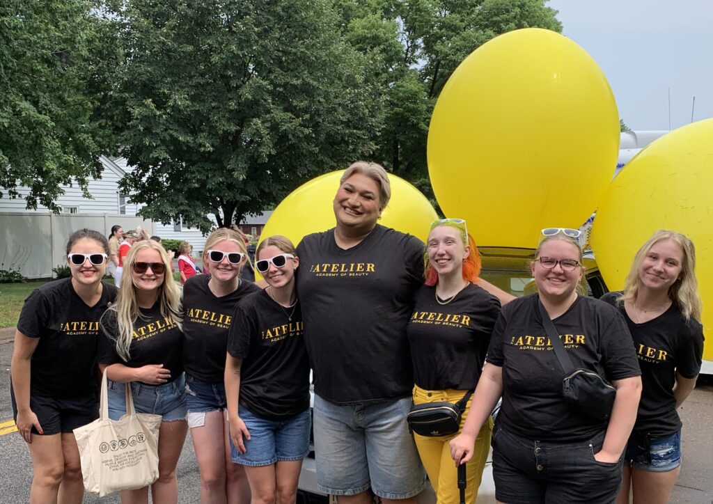 Students pose and smile at the camera wearing Atelier t-shirts